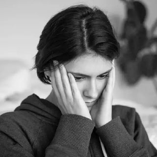 Personne fatiguée tenant son visage, illustrant les tensions liées au stress et au bruxisme.