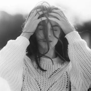 Femme en noir et blanc exprimant la fatigue émotionnelle, illustrant la tension intérieure liée au plexus solaire.