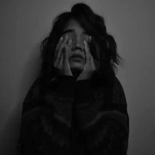 Personne épuisée, les mains sur le visage, représentant la surcharge mentale du quotidien.